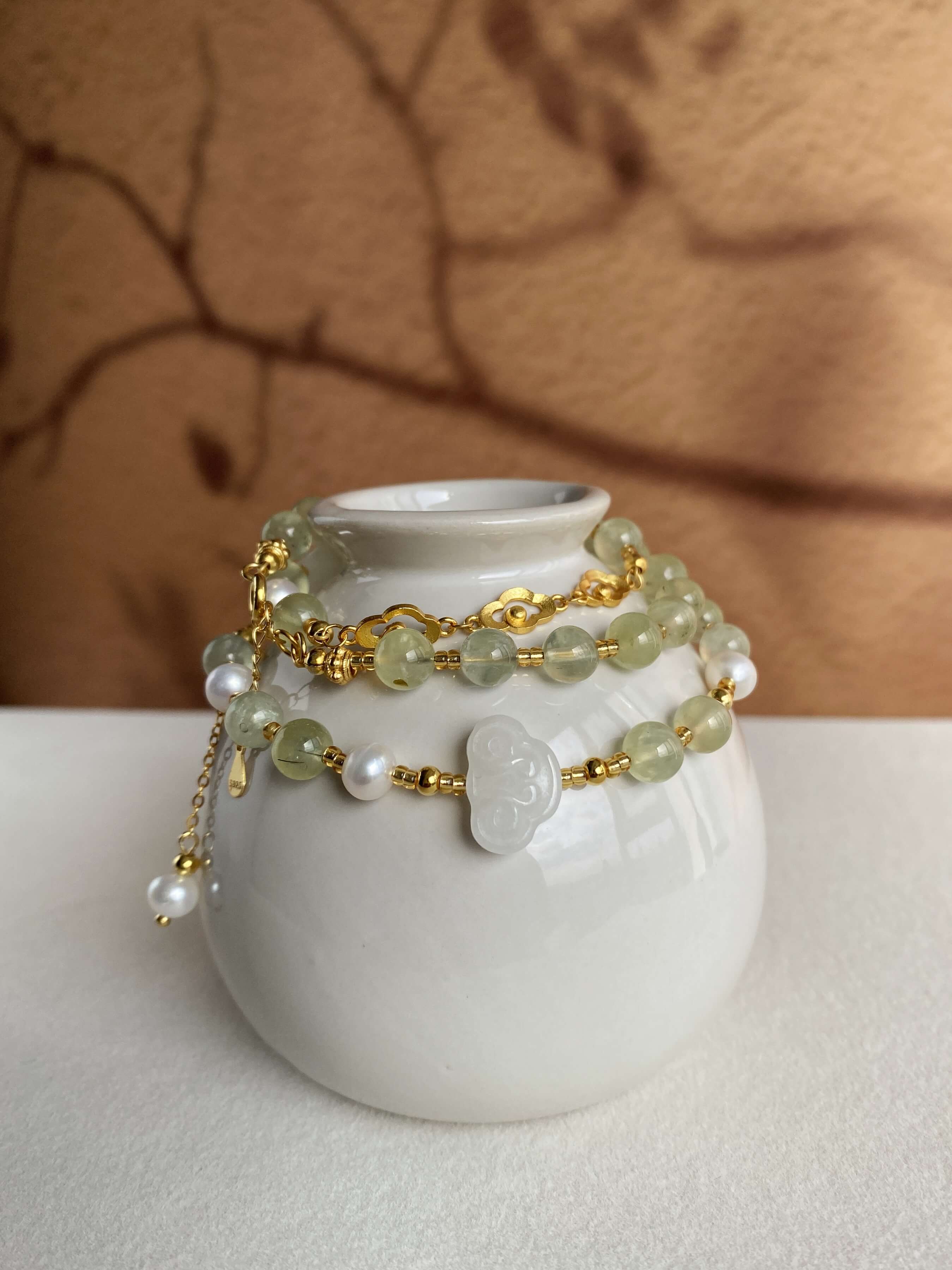 Grape Stone and Hetian Jade Necklace Displayed Wrapped Around a Vase